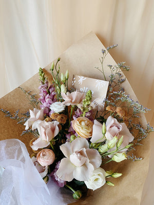 Pink purple white and coral flower bouquet wrapped in kraft paper
