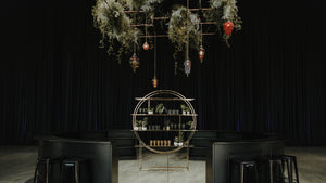 hanging greenery installations in dark room over gold bar