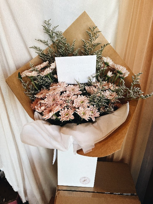 Large spray mum and limonium bouquet wrapped in kraft paper in upright delivery box. in pastel pink
