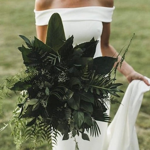 All greenery bouquet held by bride in white dress