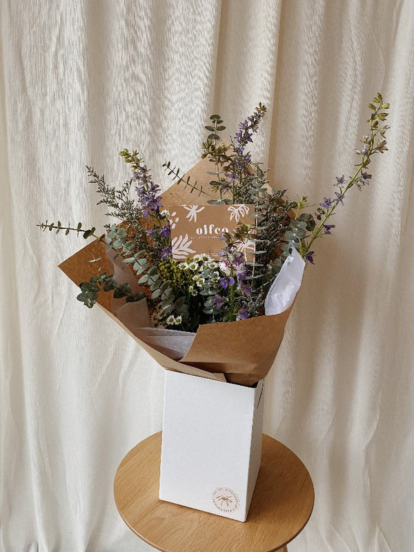 A wild looking handtied bouquet filled with baby blue eucalyptus, wild textures and flowers in blues