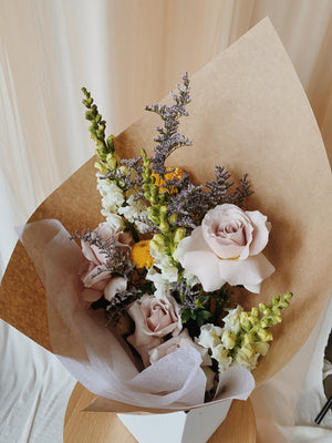 Bouquet of fresh, seasonal Flowers in pastel colours, wrapped in kraft paper and displayed in a delivery box