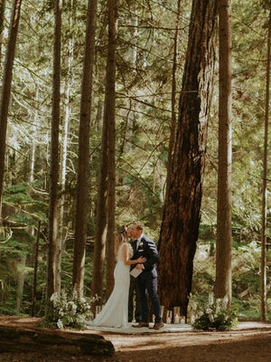 Couple wedding ceremony with 2 flower floor pieces on either side in forest