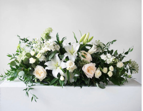 Classic casket spray with white roses and white lilies and greenery