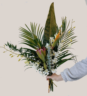 A tropical flower bouquet with palm leaves, orchids, protea and birds of paradise flower