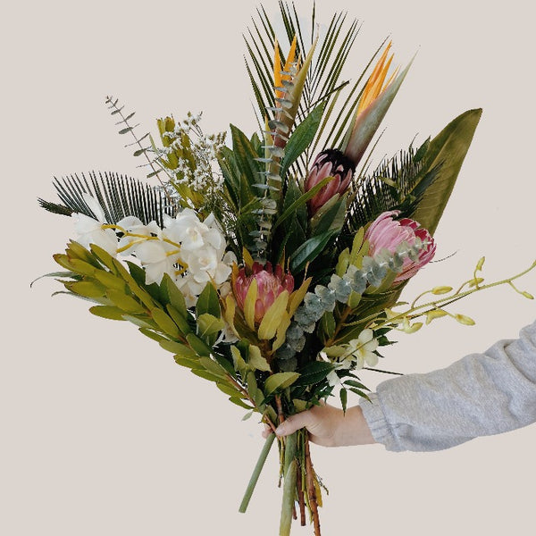 A large tropical flower bouquet with palm leaves, orchids, protea and birds of paradise flower