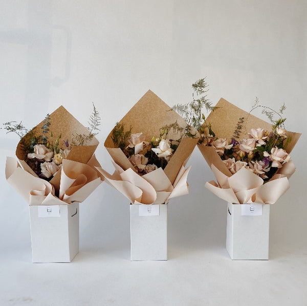 Classic Handtied bouquets displayed in upright delivery boxes in three sizes. Roses, seasonal flowers and greenery in pastel colours.