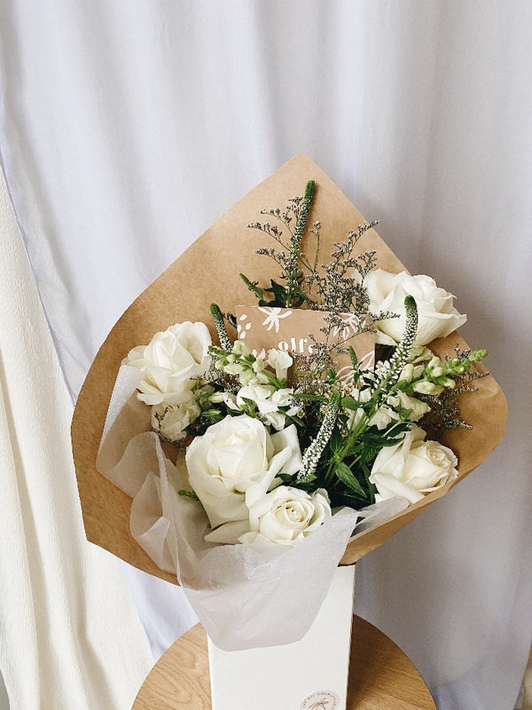 A botanical flower arrangements in a green and white colour pallet. White roses, ferns and eucalpytus